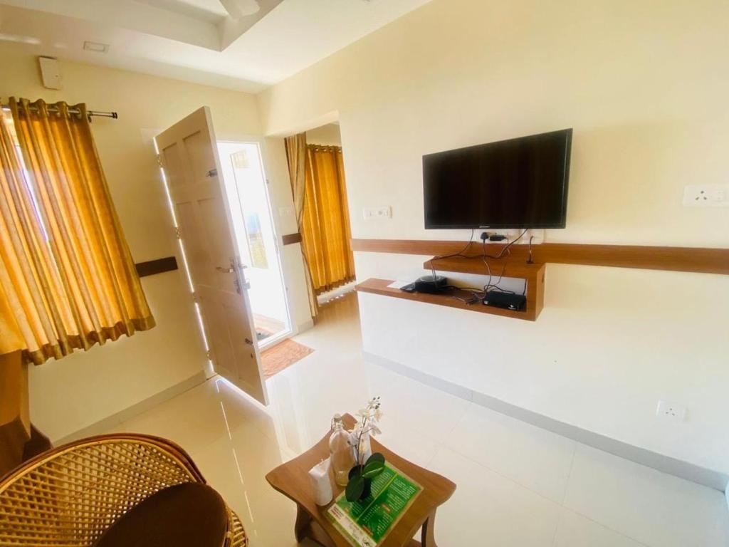 Una sala de estar con un televisor de pantalla plana en la pared. en Casa Nube Resort Munnar, en Munnar