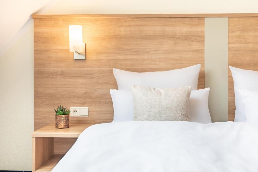 a bed with white pillows and a wooden headboard at Garner Hotel Bochum by IHG in Bochum