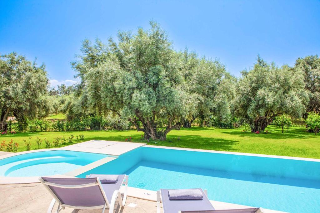 an image of a swimming pool with chairs and trees at Villa Averto Anna in Ráchi