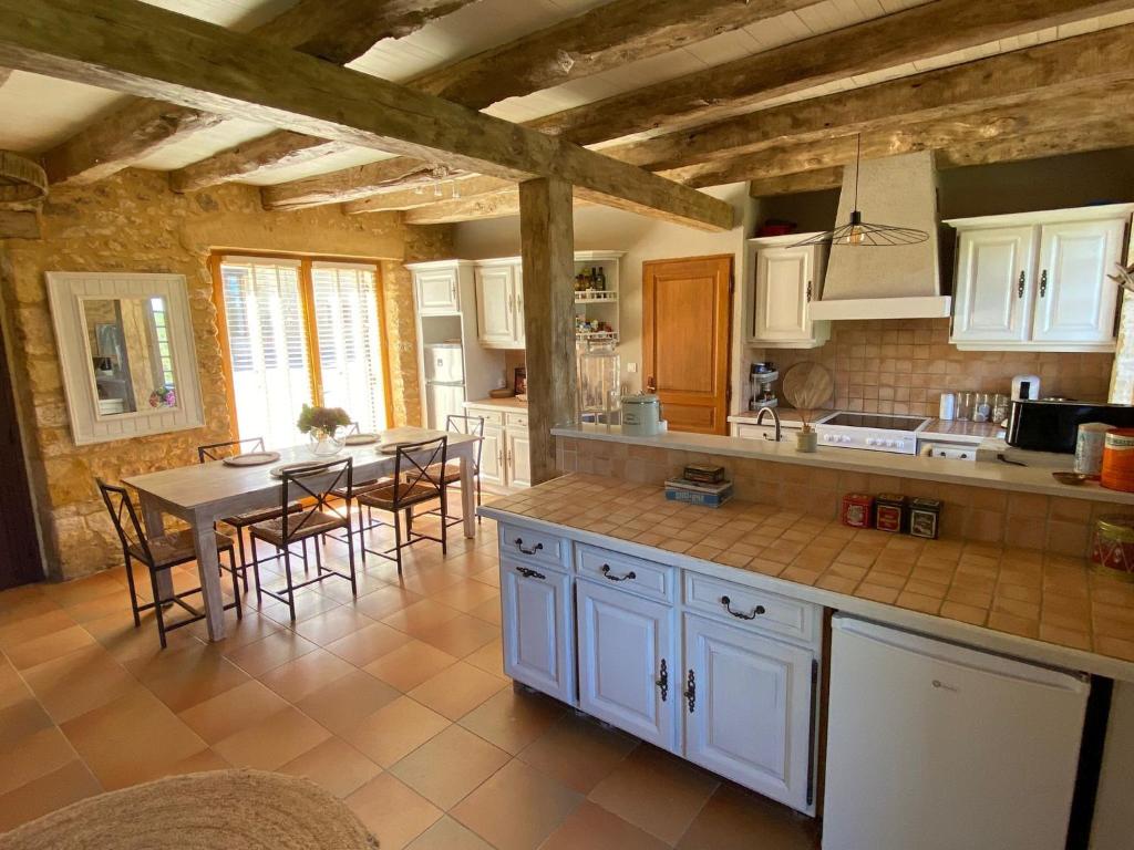 a kitchen with white cabinets and a table with chairs at Le Domaine de Camberoux La Petite Longère in Saint-Marcel-du-Périgord