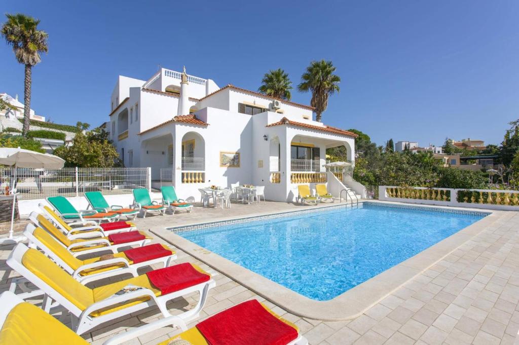 a villa with a swimming pool and lounge chairs at Villa Curva do Monte by Villa Plus in Carvoeiro