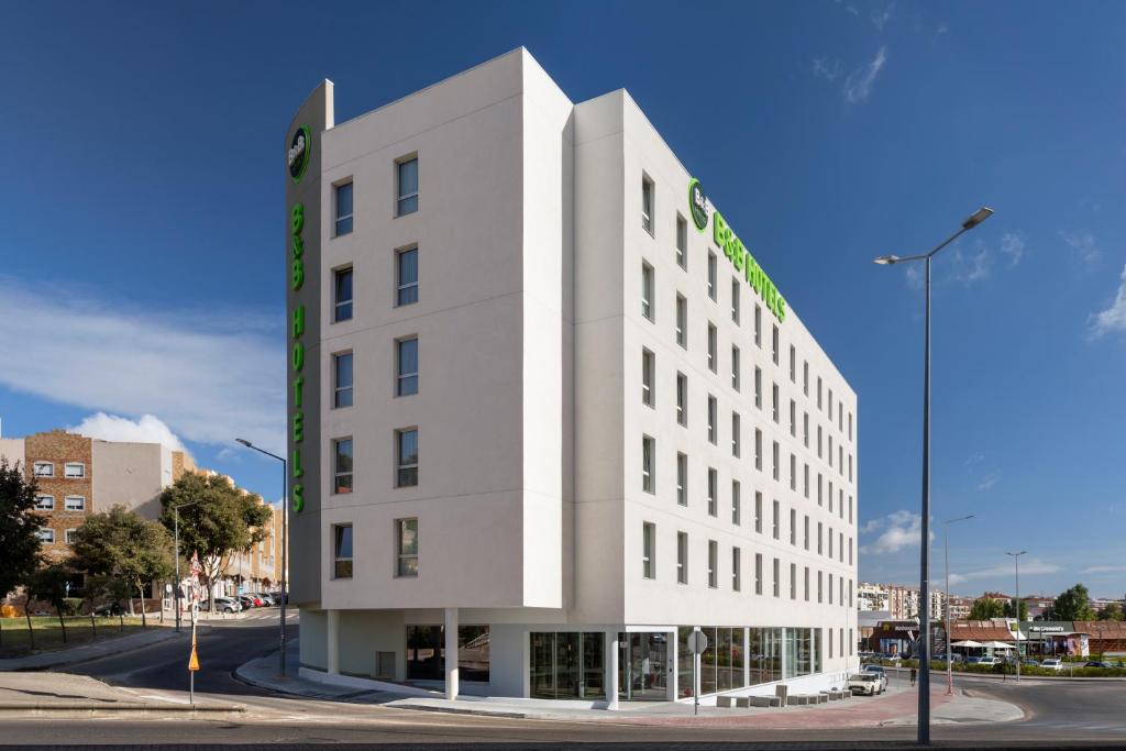 a white building with a green sign on it at B&amp;B HOTEL Setúbal Bonfim in Setúbal