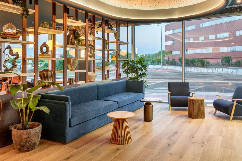 a lobby with a blue couch and chairs and tables at B&B HOTEL Setúbal Bonfim in Setúbal
