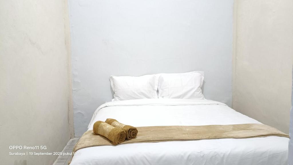 a white bed with two towels on top of it at Omah Sewu Sakura By Reccoma in Surabaya