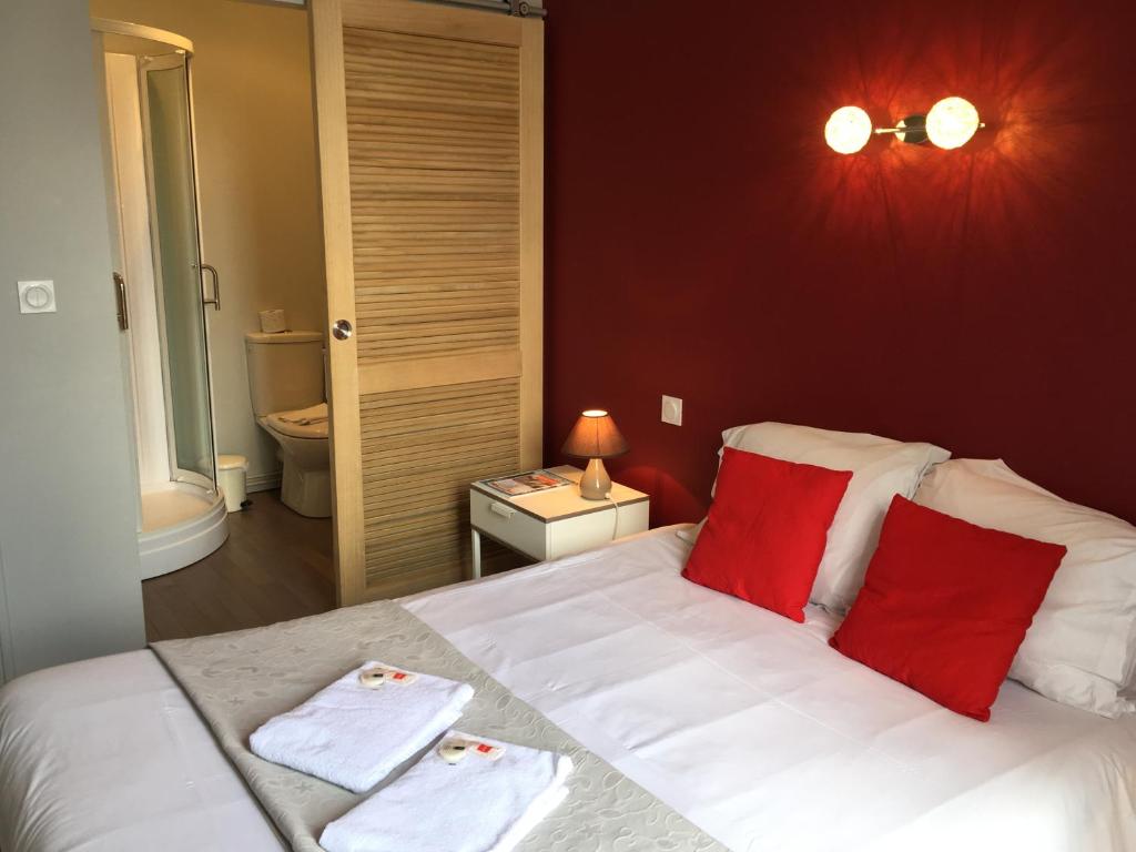 Un dormitorio con una cama con toallas rojas y blancas. en Cafe Hotel du Theatre, en Dinan