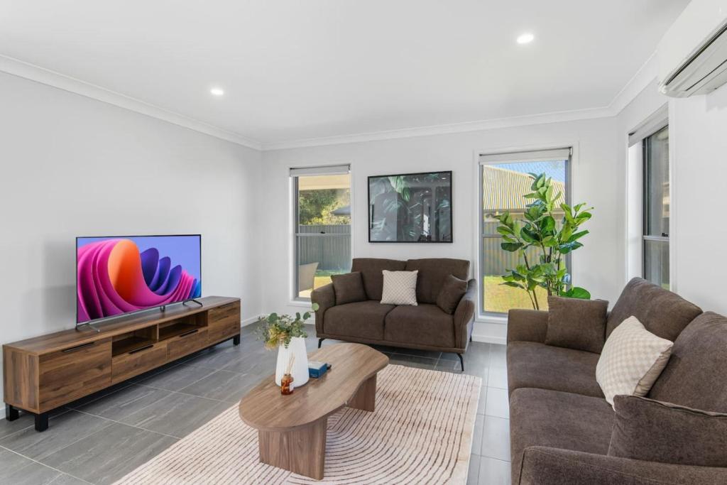 a living room with two couches and a tv at Grand and Serene Family Stay with Alfresco Living in Doolandella