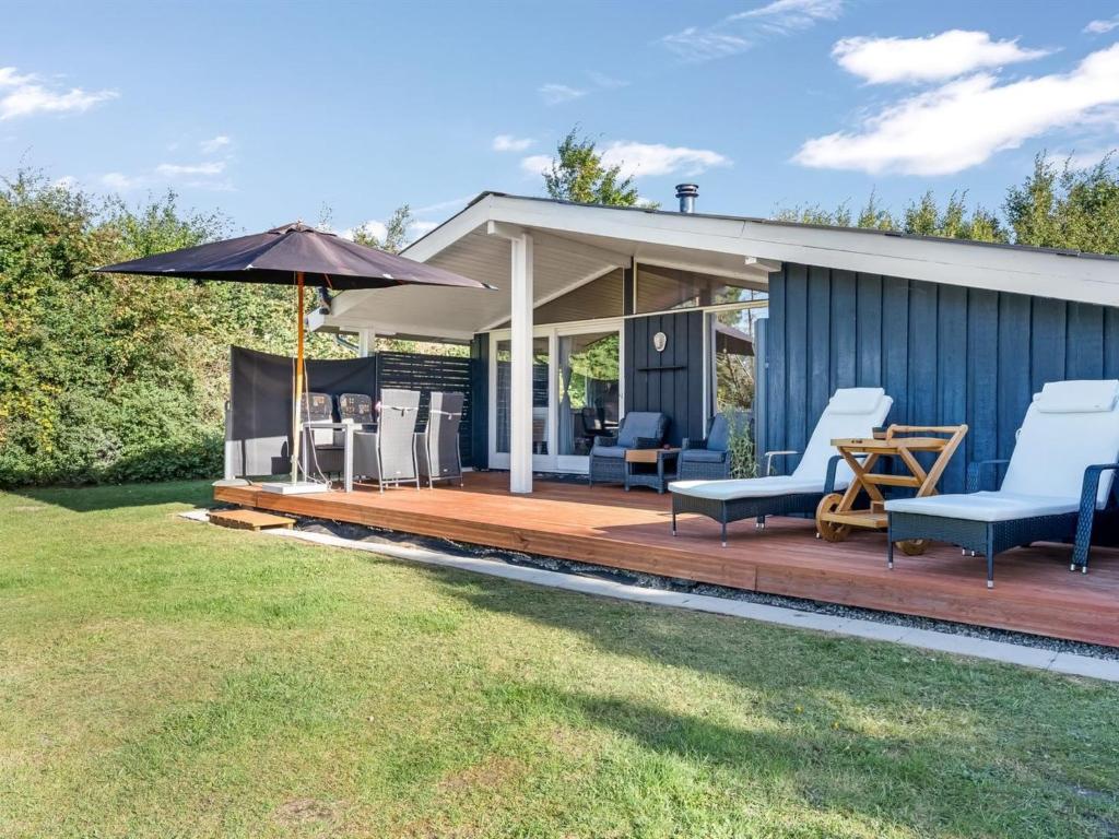 a house with a deck with chairs and an umbrella at Holiday Home Zoya - 470m from the sea by Interhome in Gedser