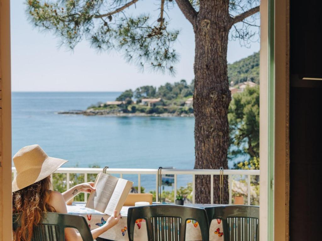 a woman sitting at a table reading a book at Apartment Le Télémaque 2 pièces Mezzanine by Interhome in Conca