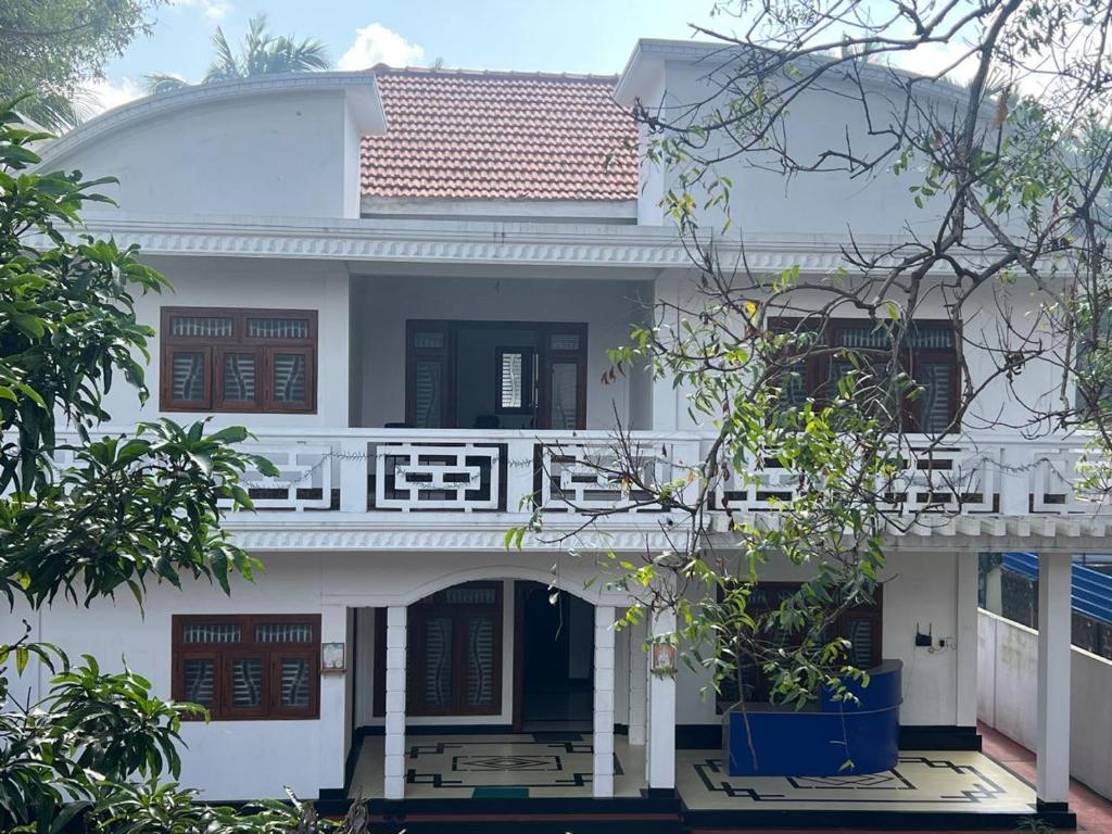 a white house with a balcony and trees at Trible R in Jaffna