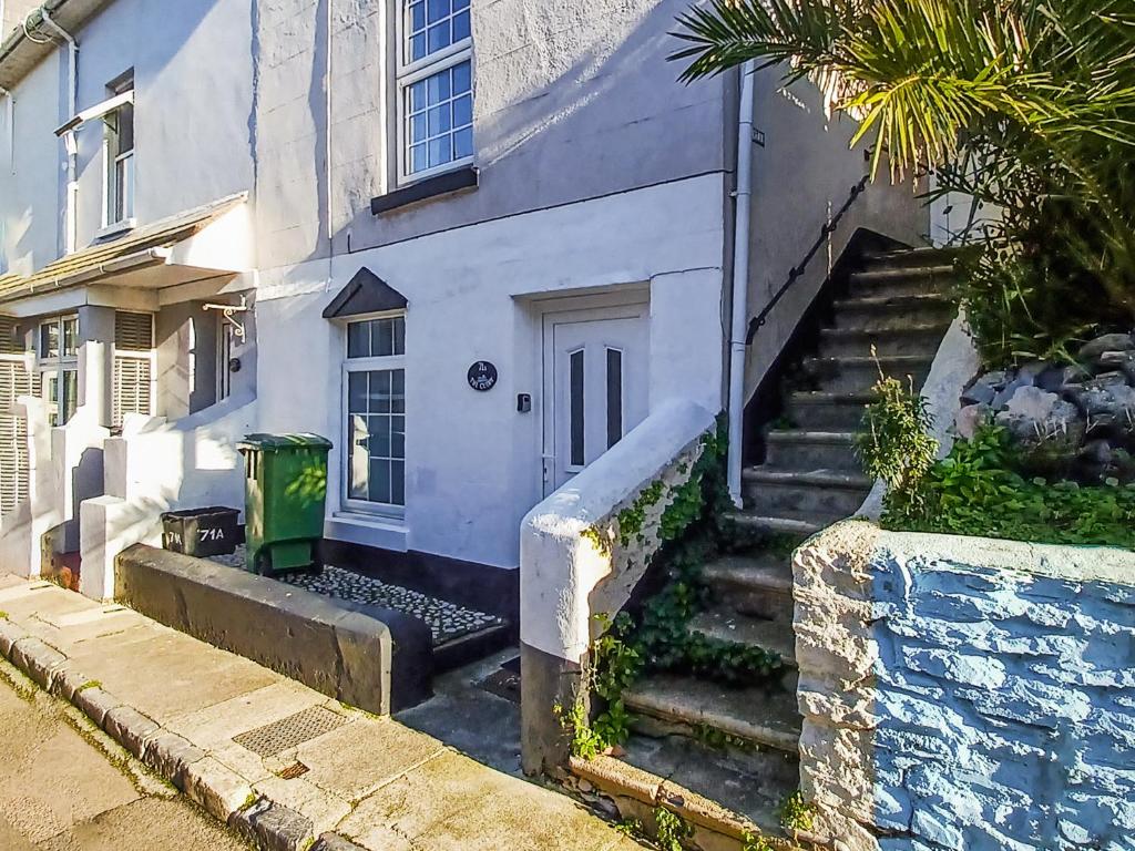 a white house with stairs leading up to a door at Rockhopper Cottage in Brixham