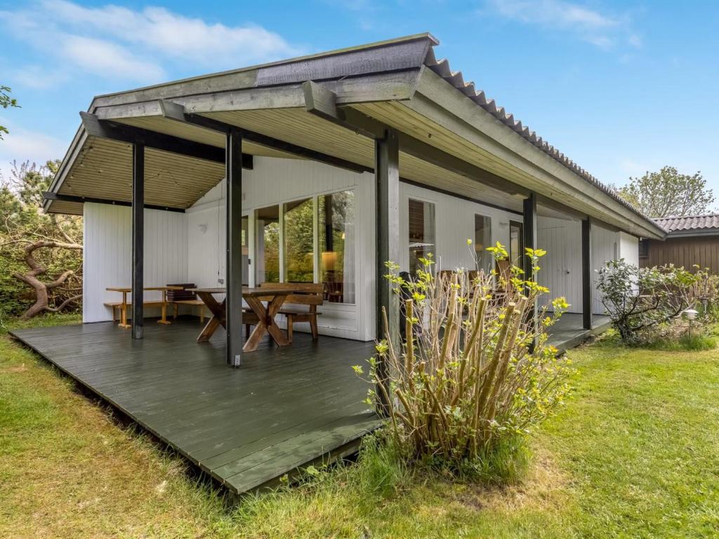 a house with a wooden deck in the yard at Holiday Home Rikkart - 400m from the sea by Interhome in Dannemare