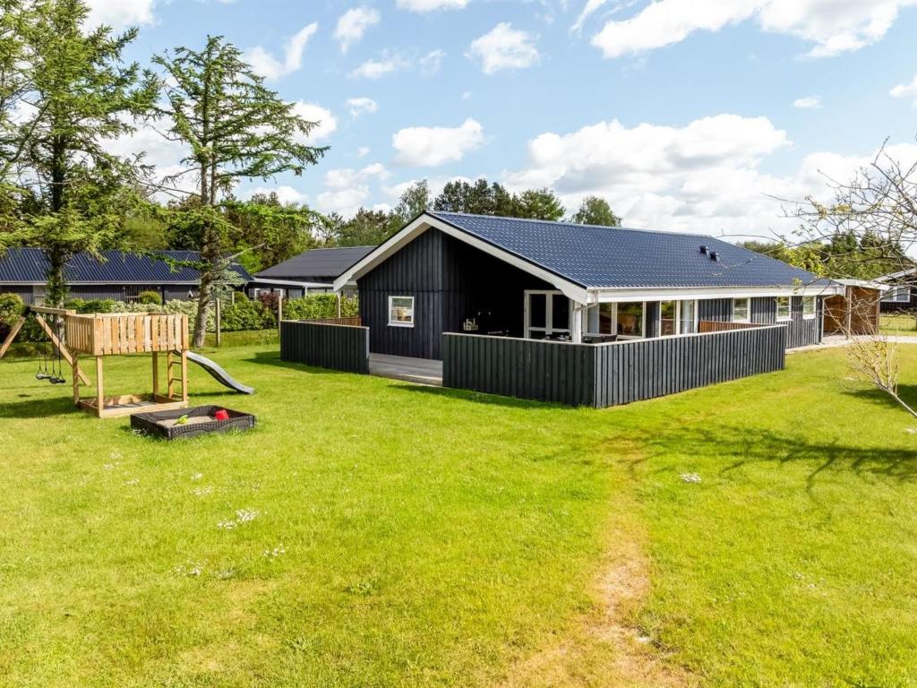 une maison noire avec une cour avec une aire de jeux dans l'établissement Holiday Home Ebertine - 740m to the inlet by Interhome, à Storvorde