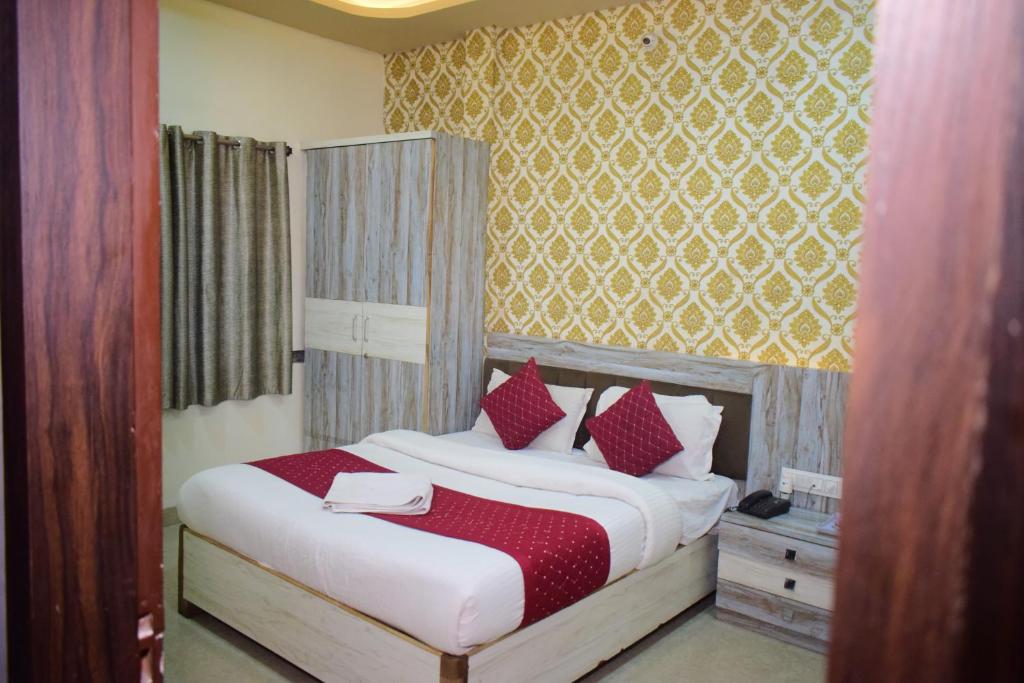 印多尔Hotel vinayak shree airport indore的卧室里有一张床，上面有红色和白色的枕头