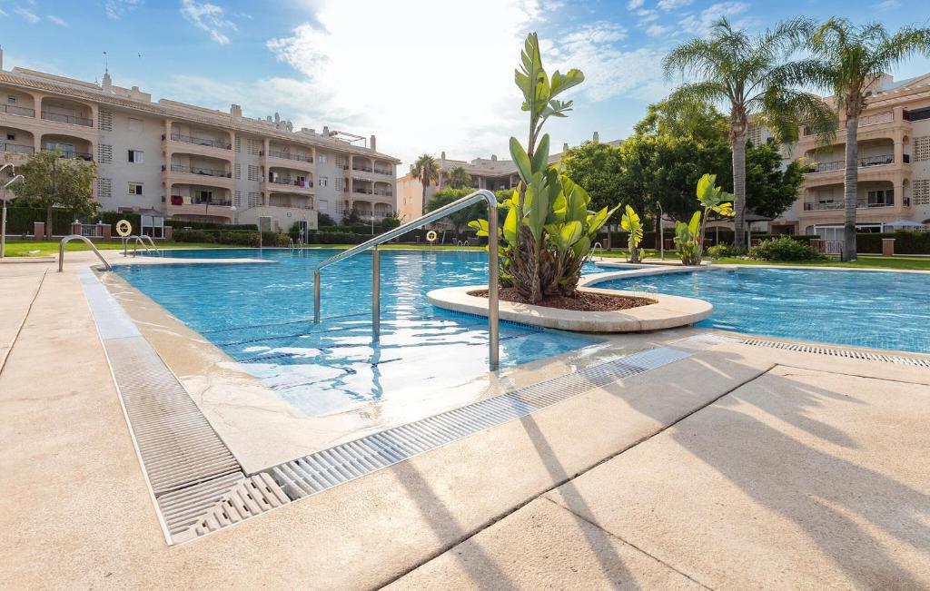 a swimming pool with a palm tree in front of a building at Great Apartment Orihuela Costa in Villamartin