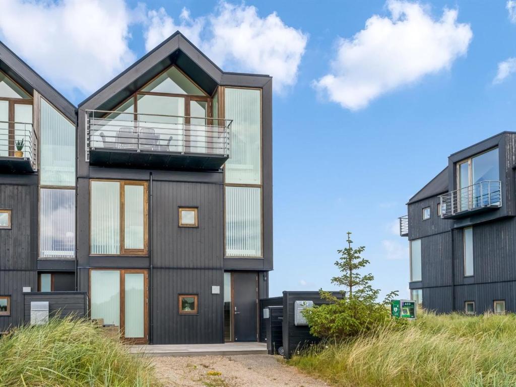 ein Haus mit schwarzer Fassade und Glasfenstern in der Unterkunft Holiday Home Anita - 575m from the sea by Interhome in Skagen