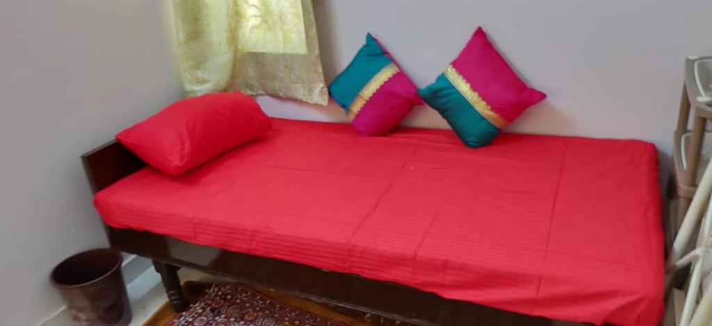 un sofá rojo con almohadas coloridas en una habitación en PG in Vadodara, en Vadodara
