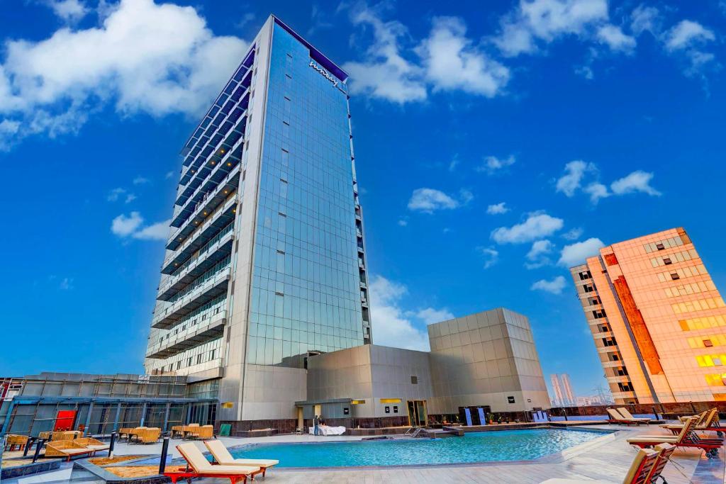 a tall building with a pool in front of it at Sunday Hotel & Residences by CheckIn, Gurugram in Gurgaon