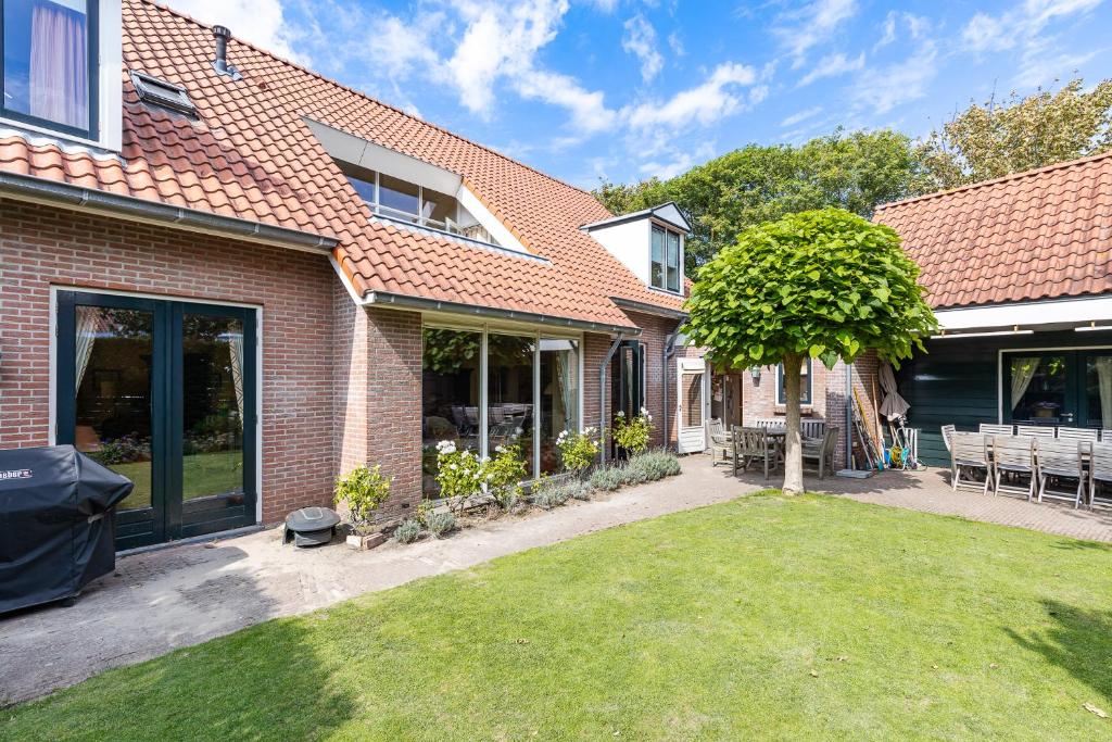 a house with a yard with a tree in it at Vrijvakantiehuis Herenhof in Domburg