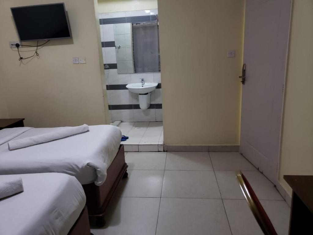 Habitación con 2 camas y baño con lavabo. en Capital Comfort Hotel, en Nairobi