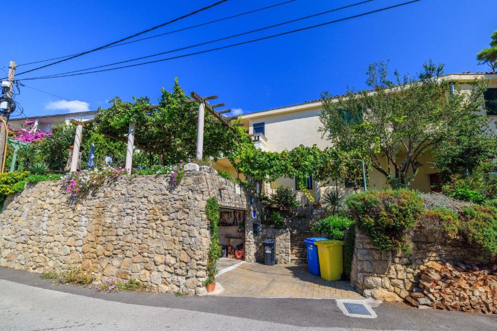 a stone wall next to a house with trees at Apartment Slavko in Mundanije