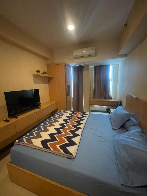 een slaapkamer met een groot bed en een flatscreen-tv bij Apartemen Anderson 28 Pakuwon mall Luxury Studio Apartment Connecting Mall, Pool & City View in Surabaya