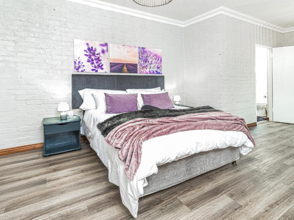 a bedroom with a large bed with purple pillows at Links & Lavender in Centurion