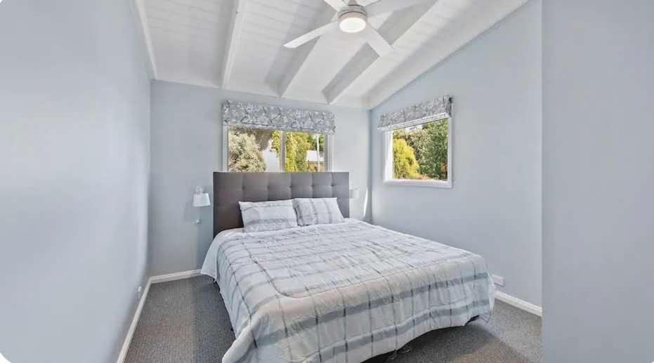 Un dormitorio blanco con una cama y un ventilador de techo. en Beautiful hill side house, en Royal Park