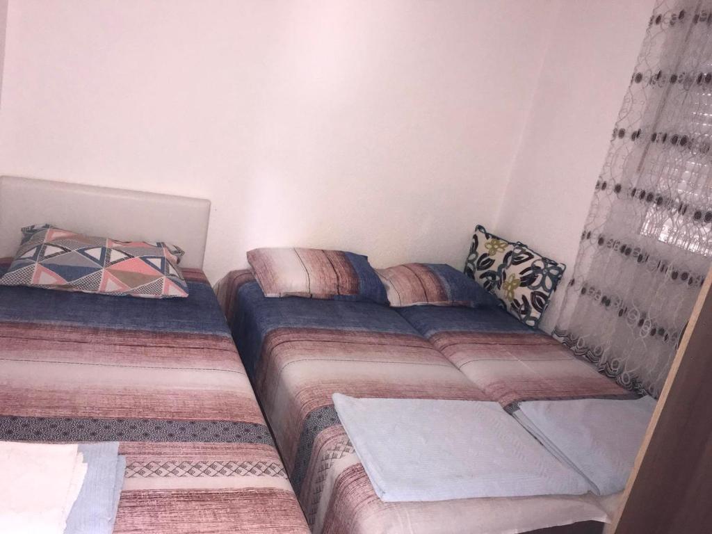 a small bedroom with two beds and curtains at Milun Stan in Sutomore