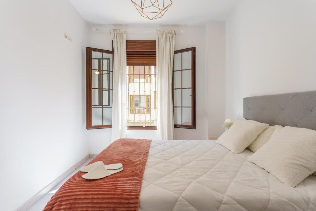 een slaapkamer met een groot wit bed met 2 schoenen erop bij Apartamentos Molino by Baiti in Ronda