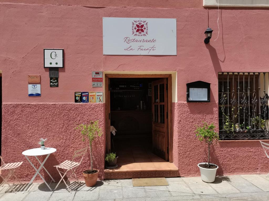 a pink building with a door and a table at Casa Rural Parada Real CR-CC-00258 in Garganta la Olla