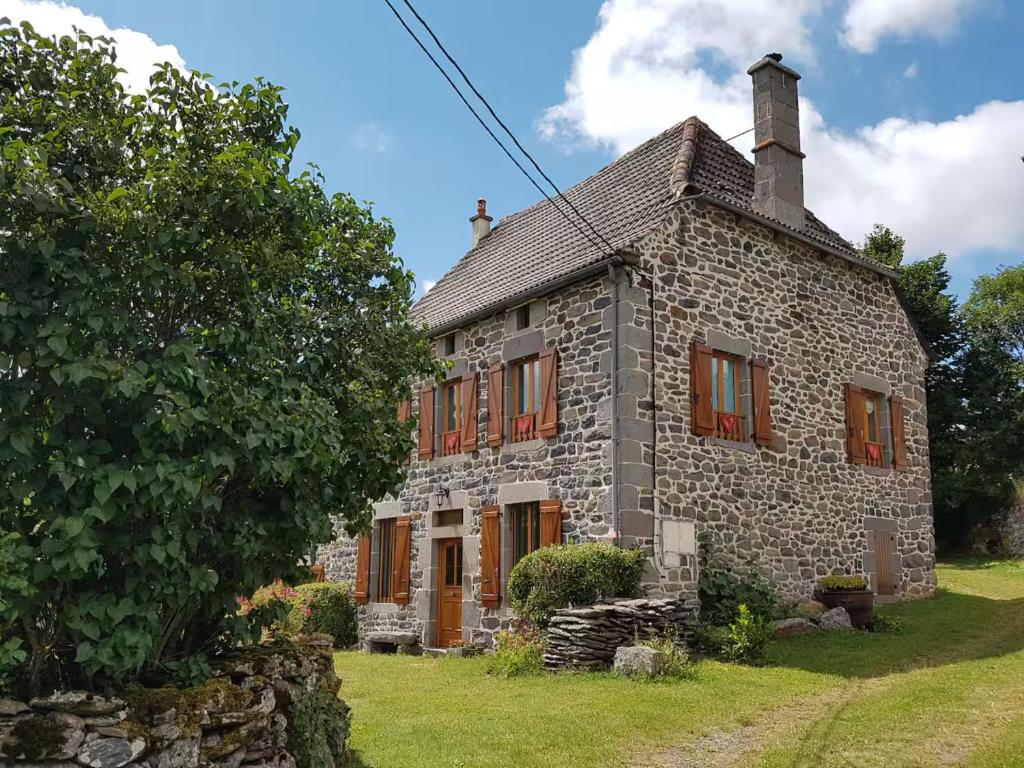Una antigua casa de piedra con ventanas con contraventanas rojas. en Chez Félicie - 2 grands gîtes, en Albepierre