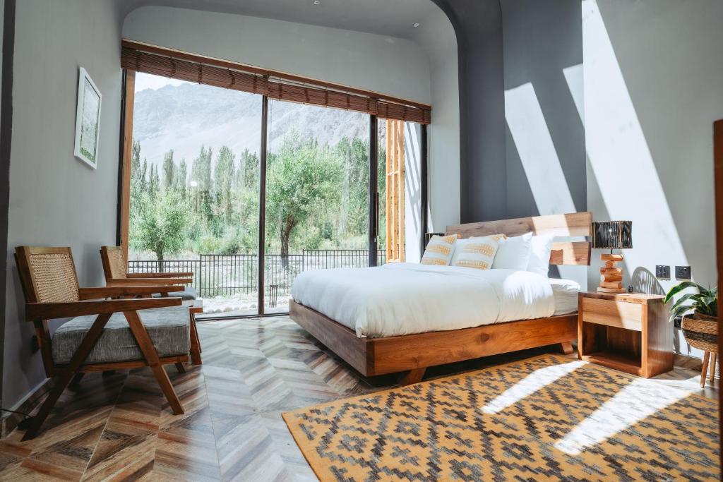 a bedroom with a bed and a large window at Rustagaarii Retreat in Yāsīn