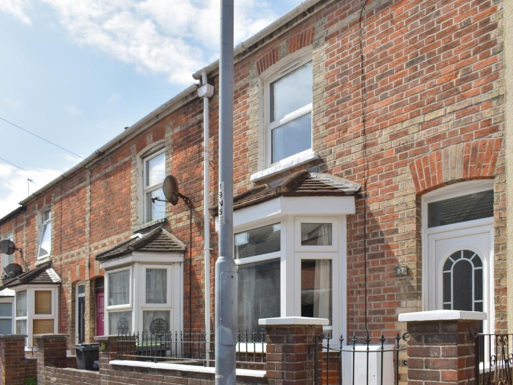 a brick house with white windows and a pole at Newstead Cottage in Weymouth