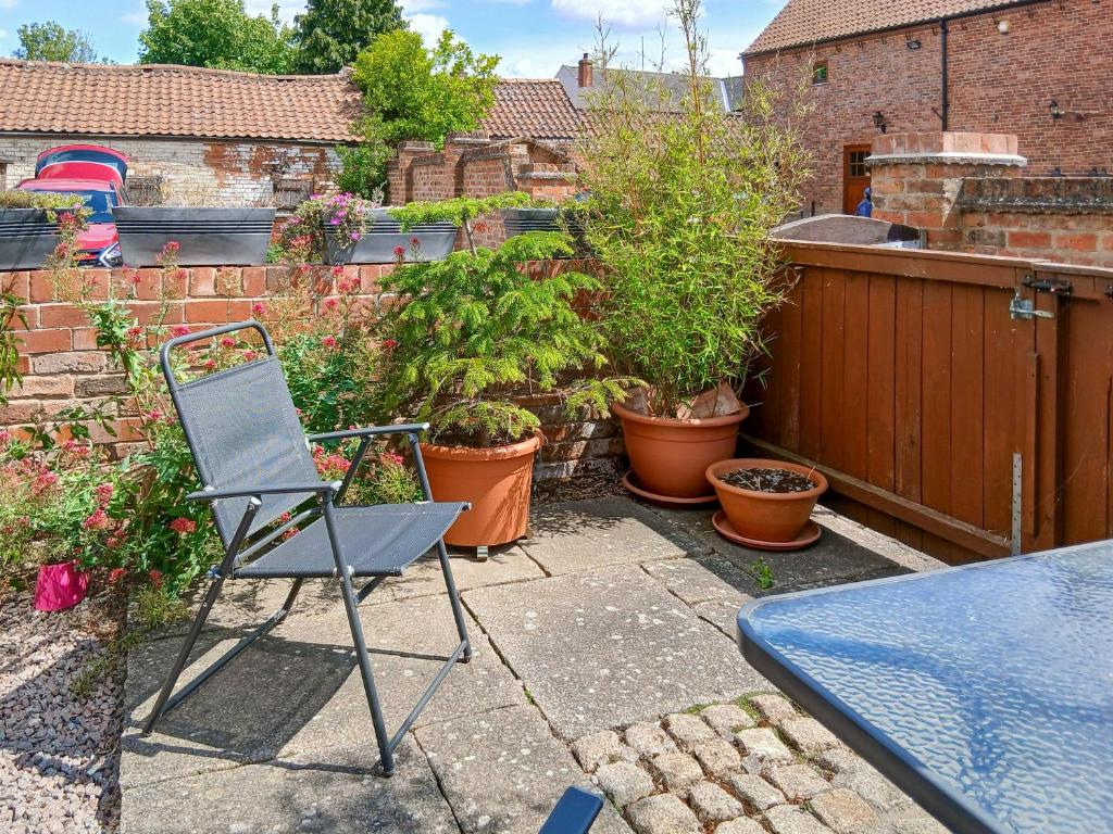a patio with a table and a chair and plants at Ikkle Cottage in Blidworth