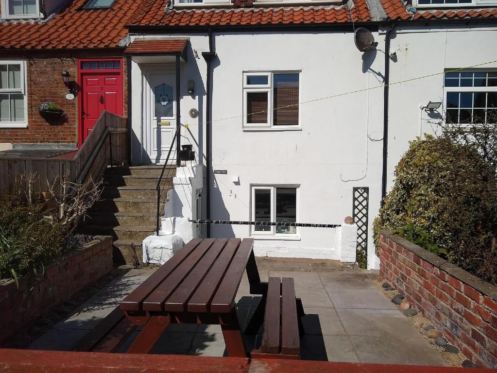 a bench in front of a house with a red door at Happy Days in Whitby