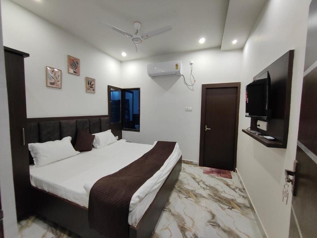 Un dormitorio con una cama y un televisor de pantalla plana. en Shri Arpanam Home Stay, en Varanasi