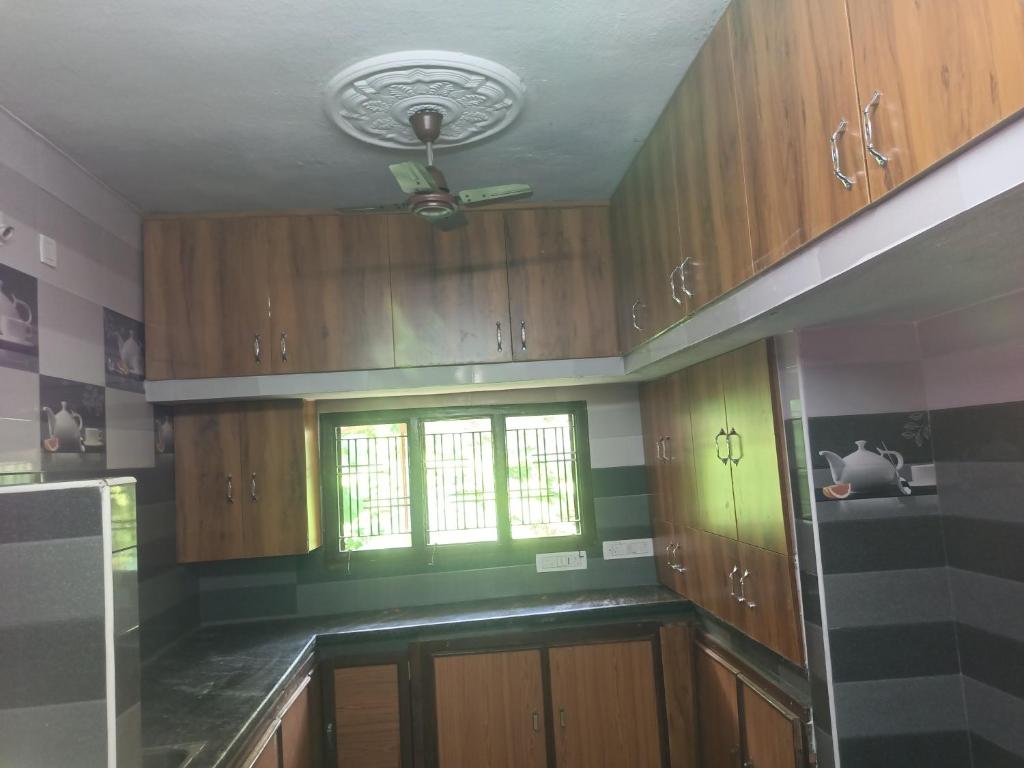a kitchen with wooden cabinets and a window at LAkSHMI HOMESTAY in Tirupati
