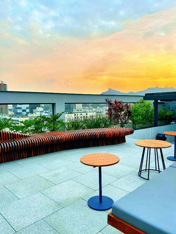 a patio with two tables and benches on a building at Estúdio sofisticado no centro do Rio com vaga de garagem in Rio de Janeiro