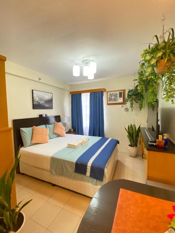 a bedroom with a large bed with blue curtains at Executive Studio Condo Unit 2 at Marina Spatial in Piapi