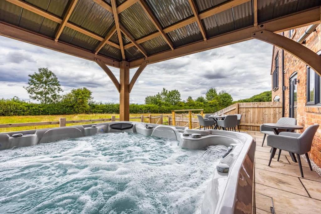 Countryside Hot Tub Games Area في Bunny: حوض استحمام ساخن على فناء مع طاولة وكراسي