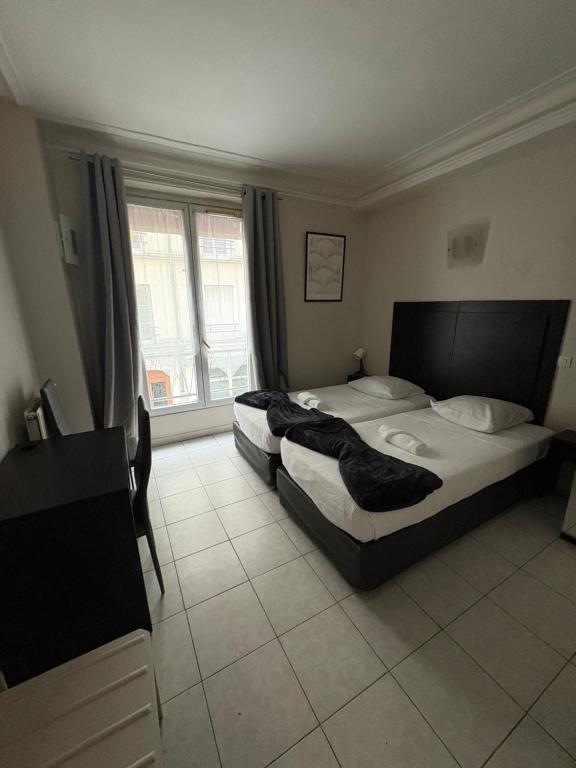 a bedroom with two beds and a large window at HOTEL DU MONT LOUIS in Paris