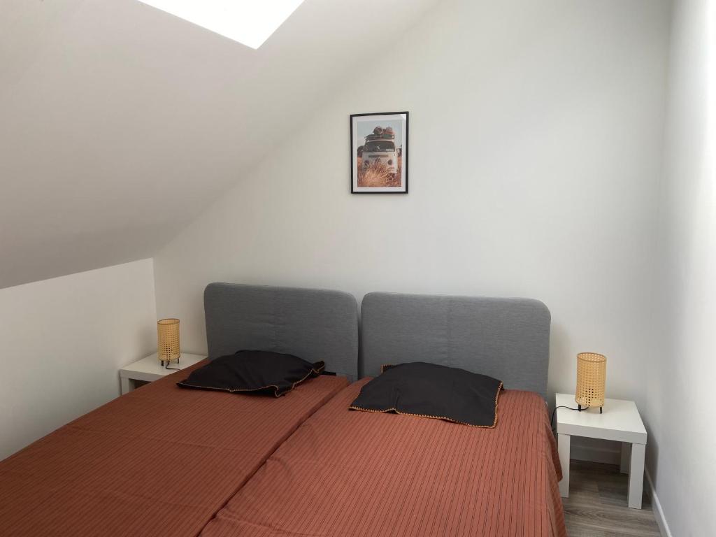 a bedroom with a bed with two pillows on it at Les COSY Apparts in Contrexéville