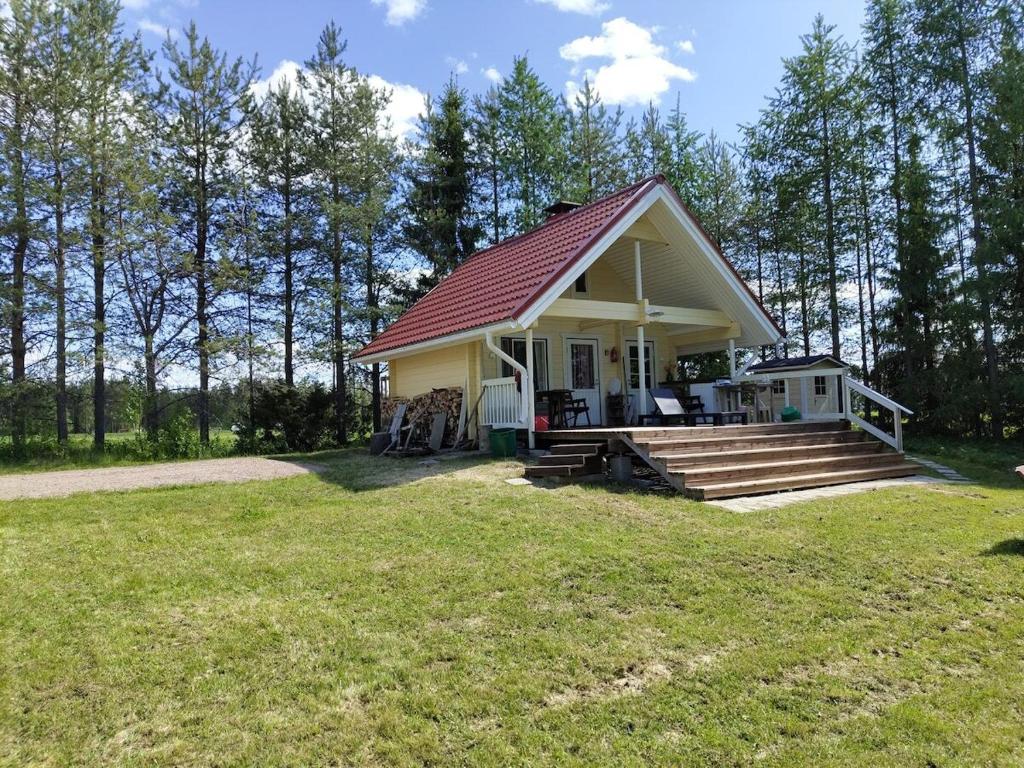 a small house with a red roof on a field at Toivon pieni rantamökki in Sonka