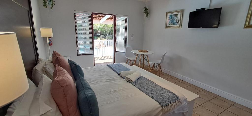 a bedroom with a bed with a television and a window at Studio 14 @ The Dunes in Plettenberg Bay