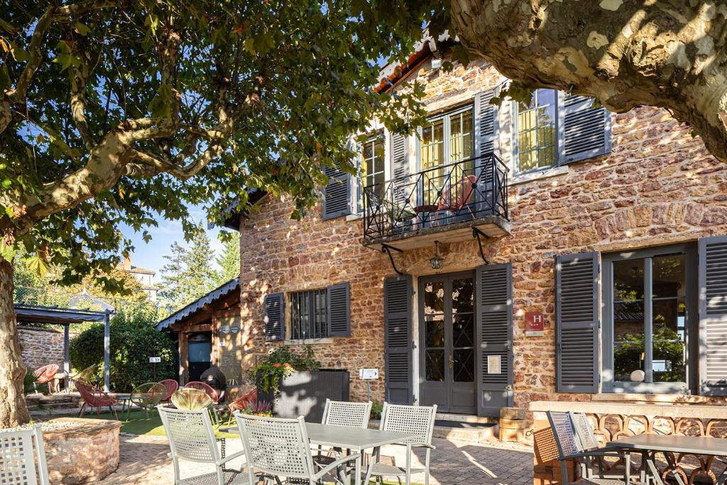 a brick building with a table and chairs in front of it at Contact Hôtels Le Savigny & Spa in Blacé