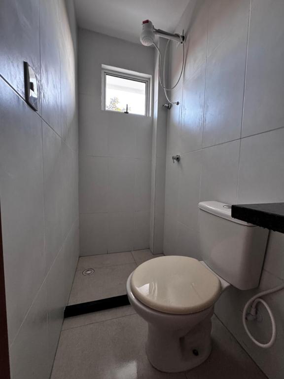Un baño blanco con inodoro y ventana. en Flat 105, en Tamandaré