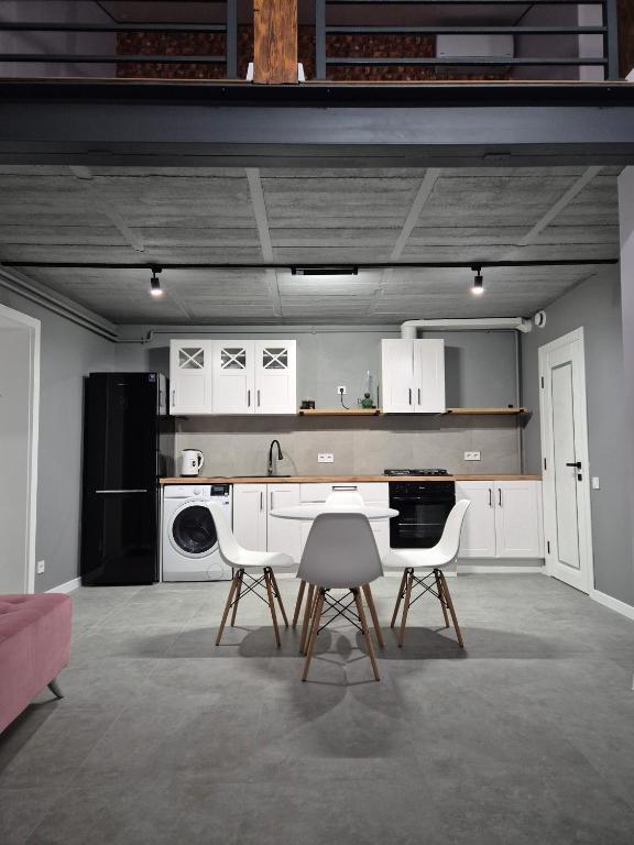 a kitchen with white cabinets and a table and chairs at Exclusive Apartments "Lviv Vernygory 14", Modern Apartments with Self Check-in in Lviv
