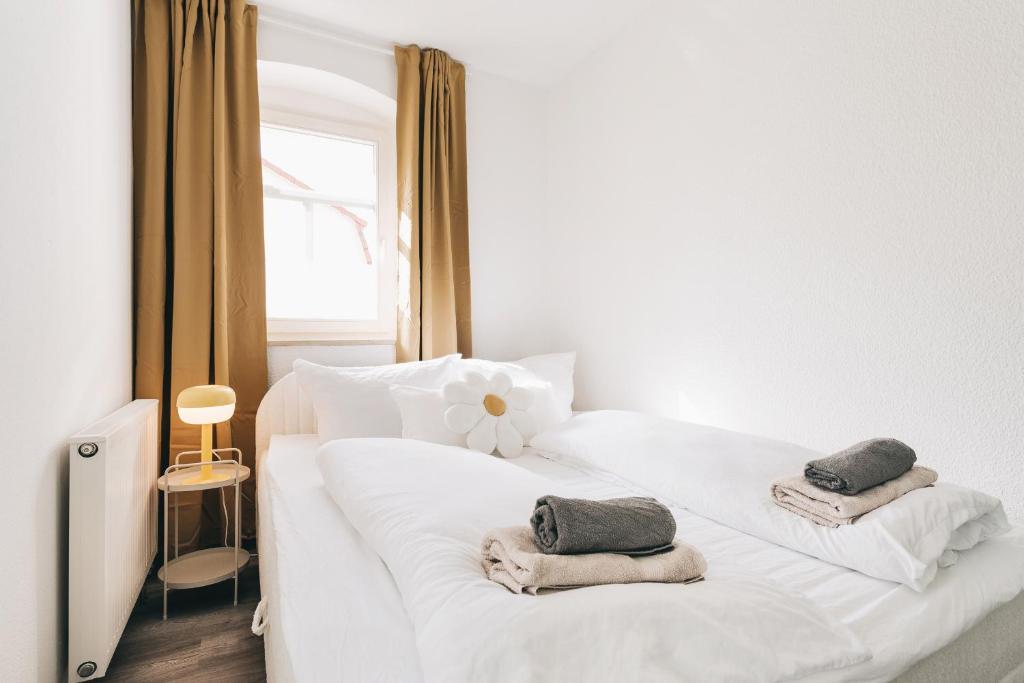 a bedroom with a white bed with towels on it at Creekside Colors - Playful Apartment in Löbau