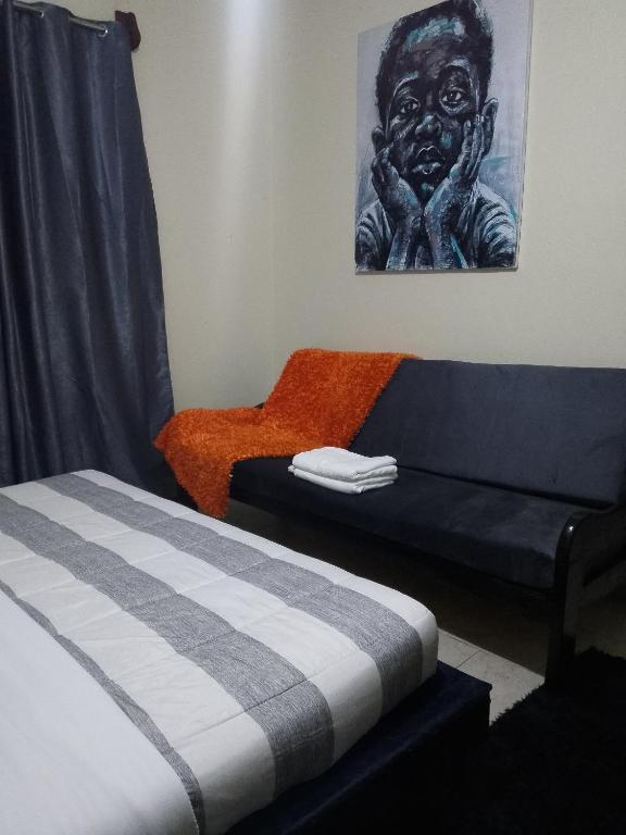 a room with a bed and a couch and a painting at Speke homes and apartments 2 in Kabale
