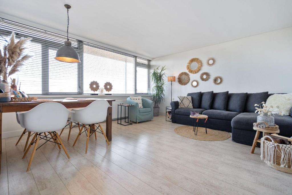 a living room with a blue couch and a table at Appartement De Kokkel Free Parking in Zandvoort